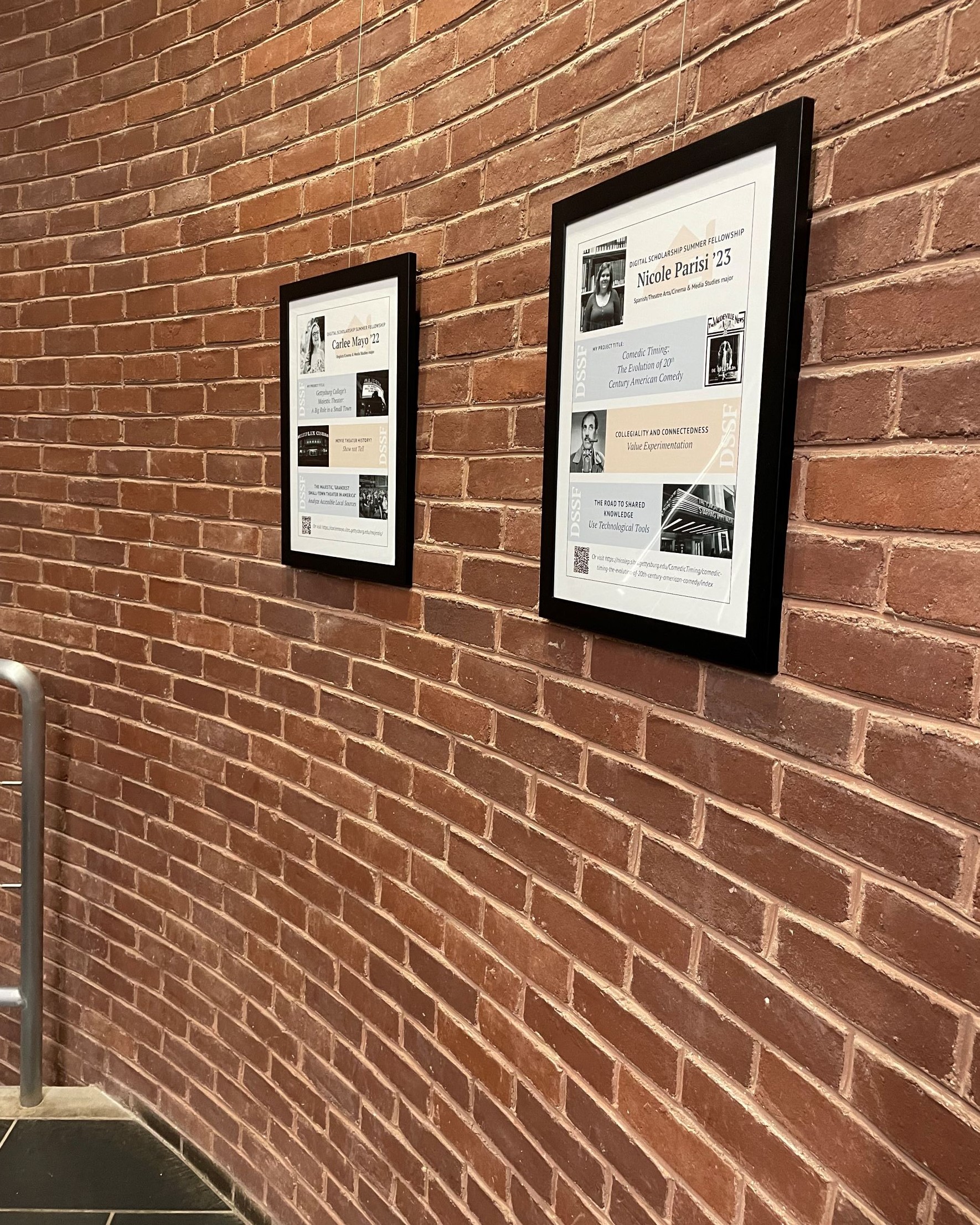 Two framed student project posters on brick wall